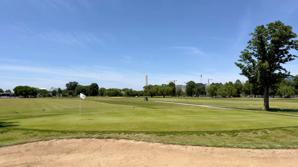 East Potomac Golf Links White Course ninth green with greenside bunker, Washington Monument visible down the eighth fairway.