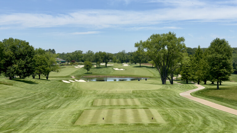 Downhill view from the elevated 9th tee at River Bend Golf & Country Club to a green fronted by a pond and guarded by bunkers